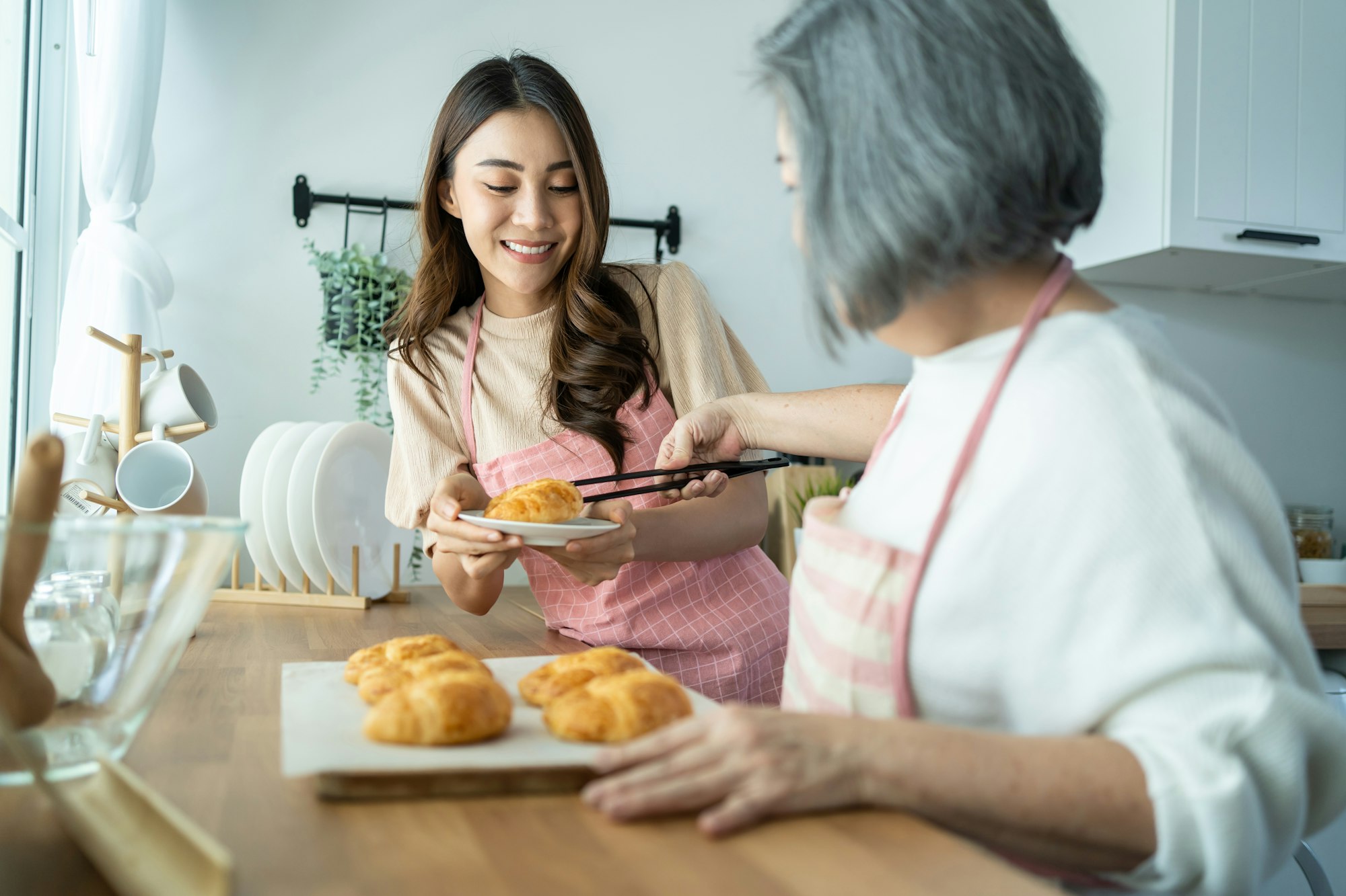 Asian lovely family, young daughter look to old mother cook in kitchen.
