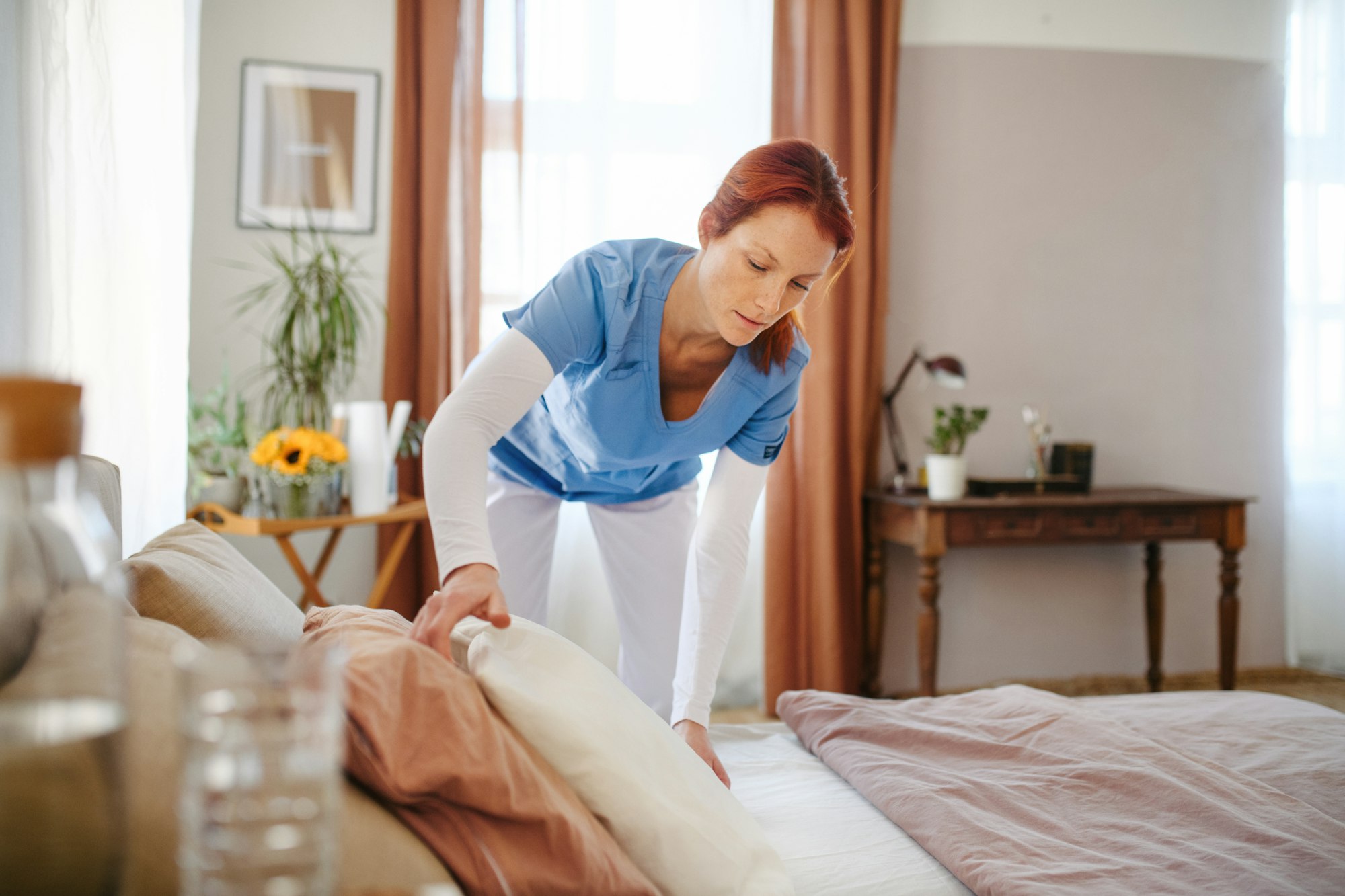 Caregiver making the bed at clients home.