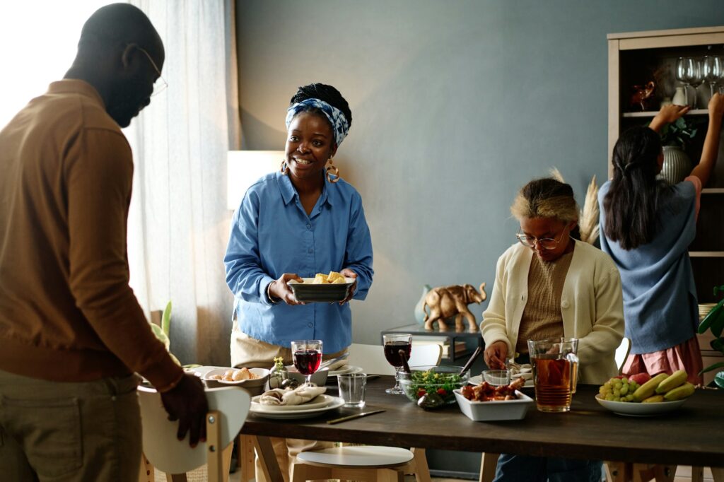 Happy young African American woman with cooked food looking at her husband