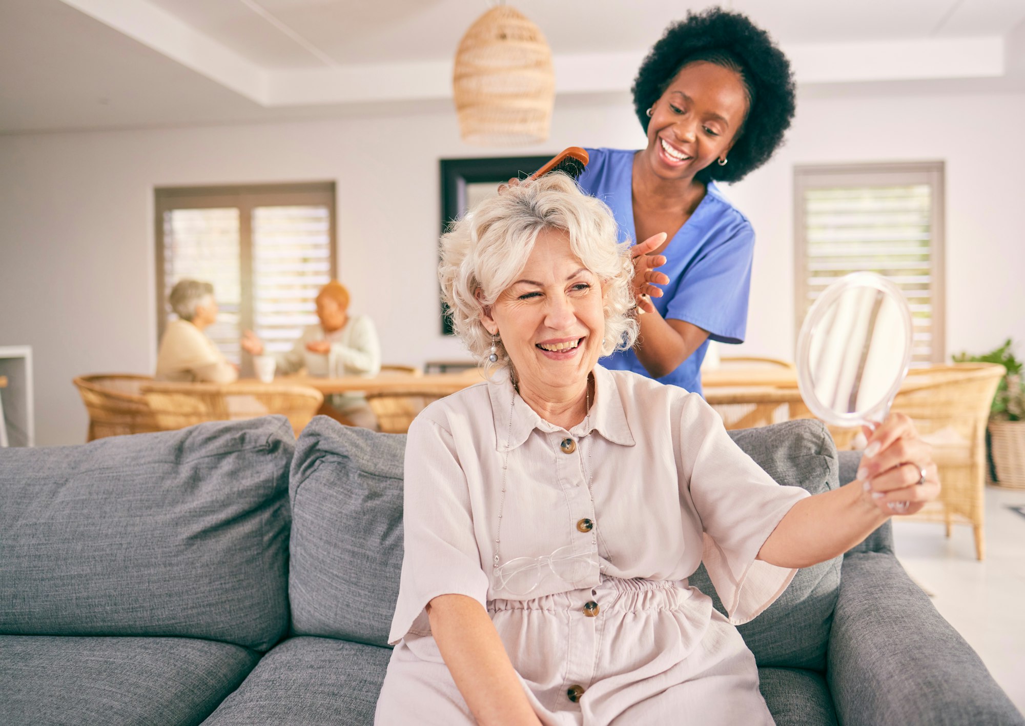 Nurse brush hair of happy mature woman in the living room of the modern retirement home for self ca