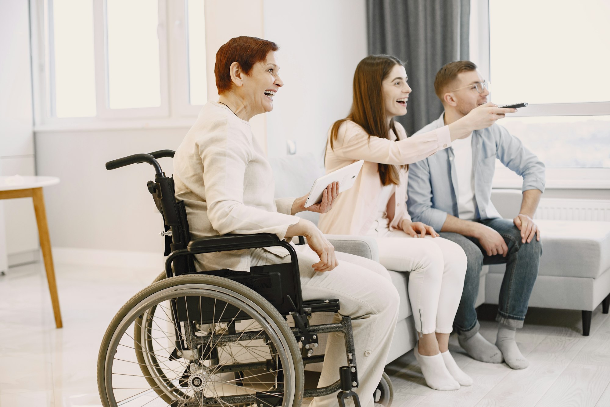 Woman in wheelchair watch tv with caregivers
