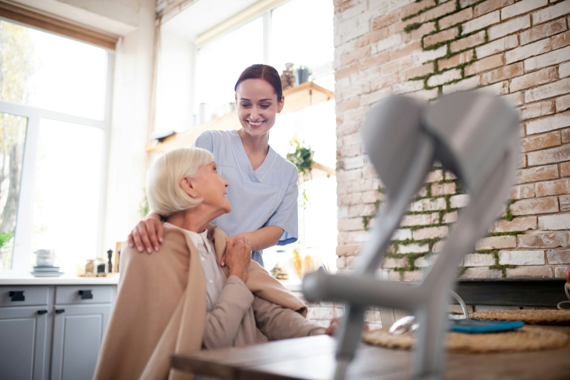 Young caregiver in uniform speaking with patient